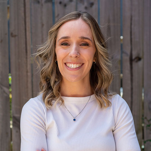 Ellie Thompson, an accredited dietitian, smiles with her arms crossed, embodying confidence in her expertise in nutrition.