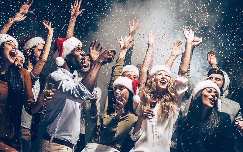 A joyful group of people celebrating Christmas, surrounded by colorful confetti, embodying festive cheer and togetherness.