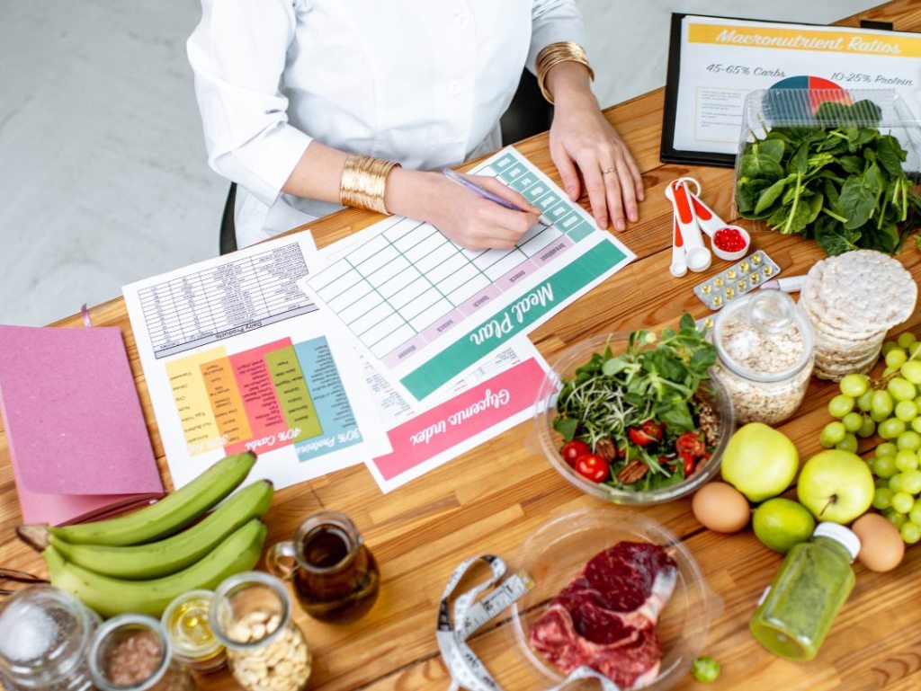 A woman sits at a table filled with various foods, focusing on an endometriosis-friendly diet for better health.