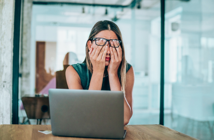 Female entrepreneur with headache at desk, highlighting the importance of corporate nutrition programs services and workplace dietitian services